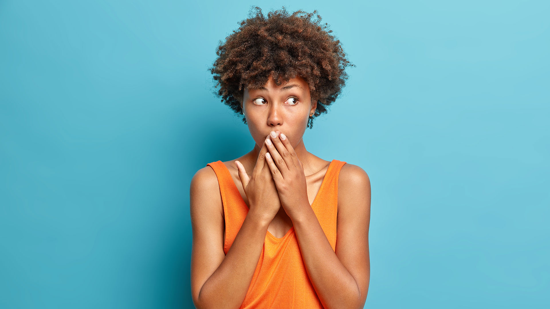 Ragazza che si copre il sorriso con le mani perché a disagio con i suoi denti macchiati