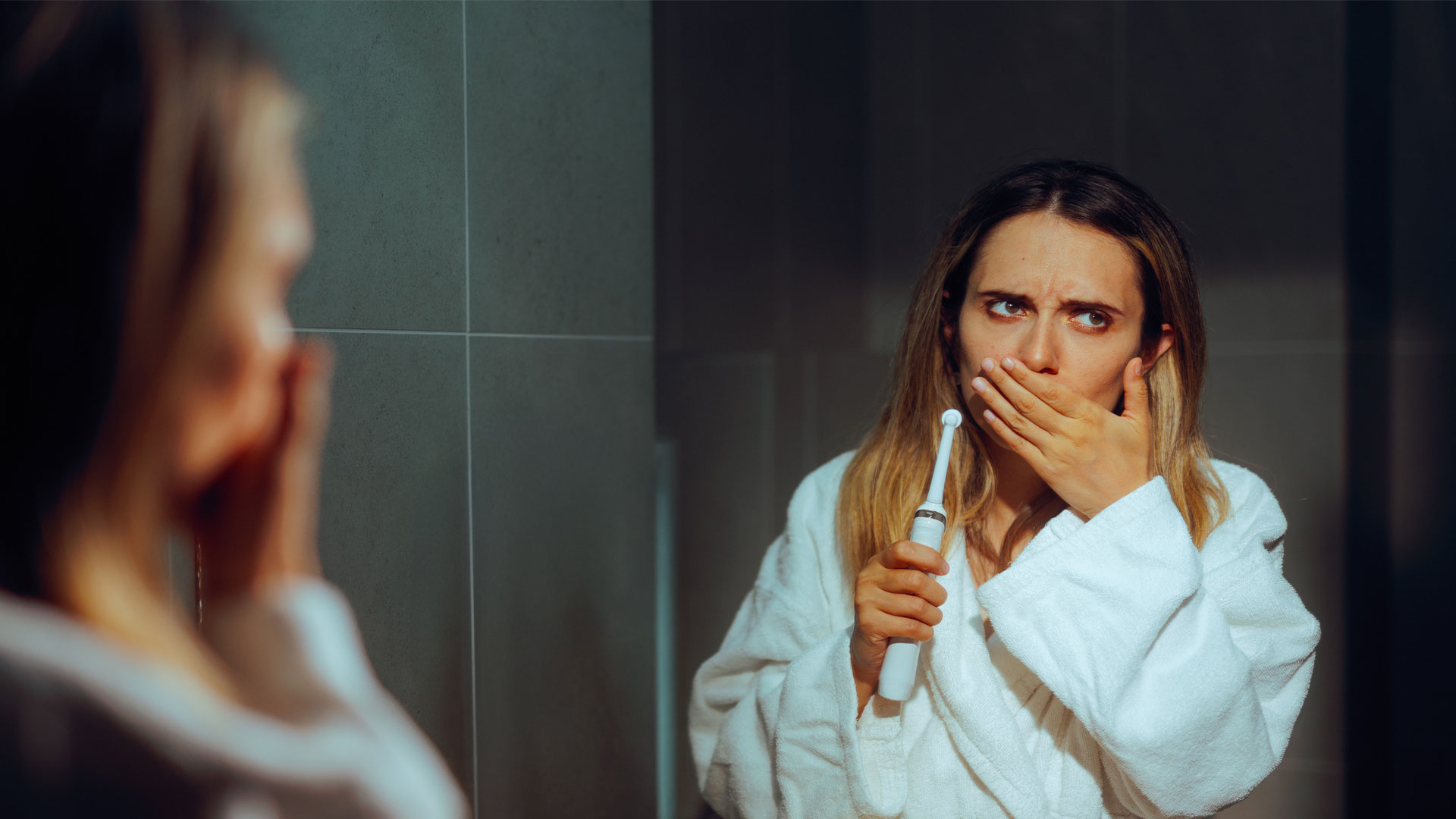 Foto di una ragazza che soffre di sensibilità ai denti perché ha una recessione gengivale