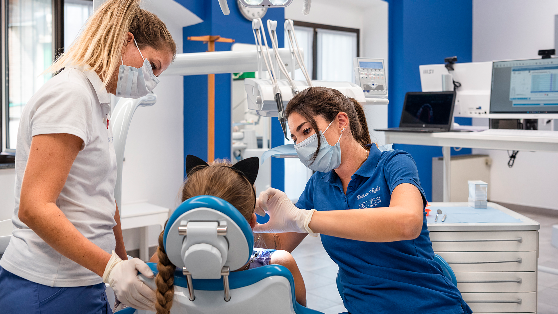 Foto di una piccola paziente seduta sulla poltrona del dentista mentre la stanno visitando per il morso crociato lateale