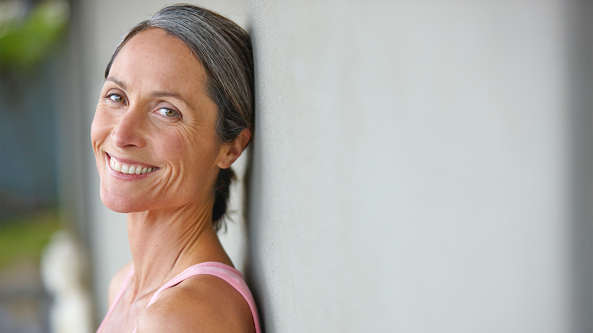 Foto di una donna che sorride mettendo in evidenza le rughe del contorno occhi