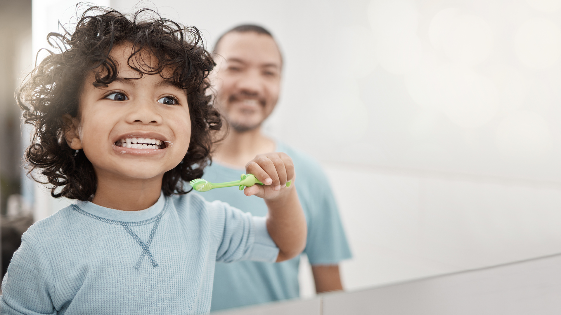 Foto di un bambino che si lava i denti sotto la supervisione del papà